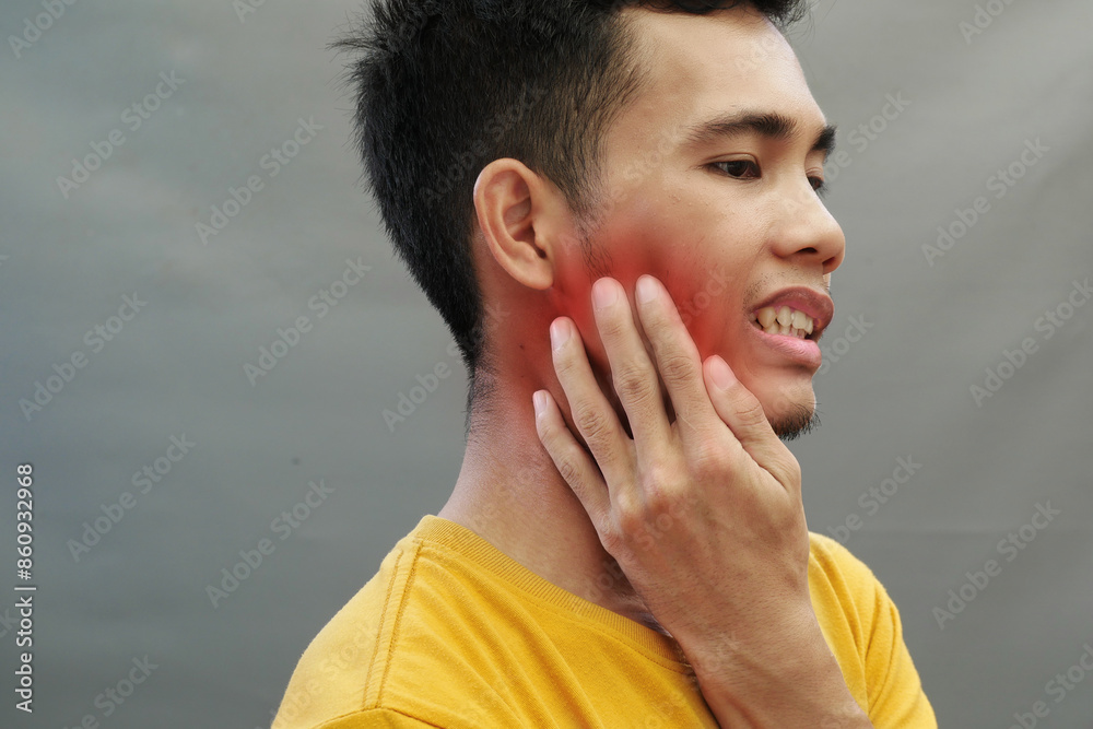 An Asian man holds his jaw with a toothache with an expression of pain, the area of pain is highlighted in red An Asian man holds his jaw with a toothache with an expression of pain, the area of pain is highlighted in red