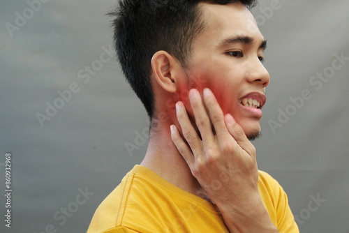 An Asian man holds his jaw with a toothache with an expression of pain, the area of ​​pain is highlighted in red photo