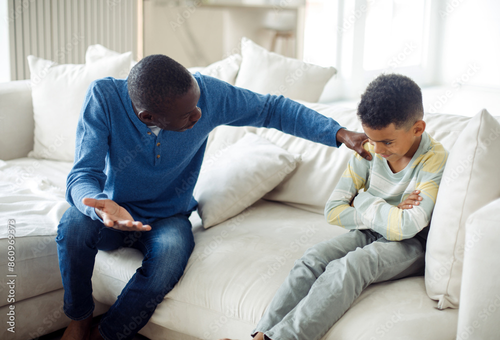 A dissatisfied African dad explains to his little son what he is doing wrong. Conflict between father and son. A dissatisfied African dad explains to his little son what he is doing wrong. Conflict between father and son.