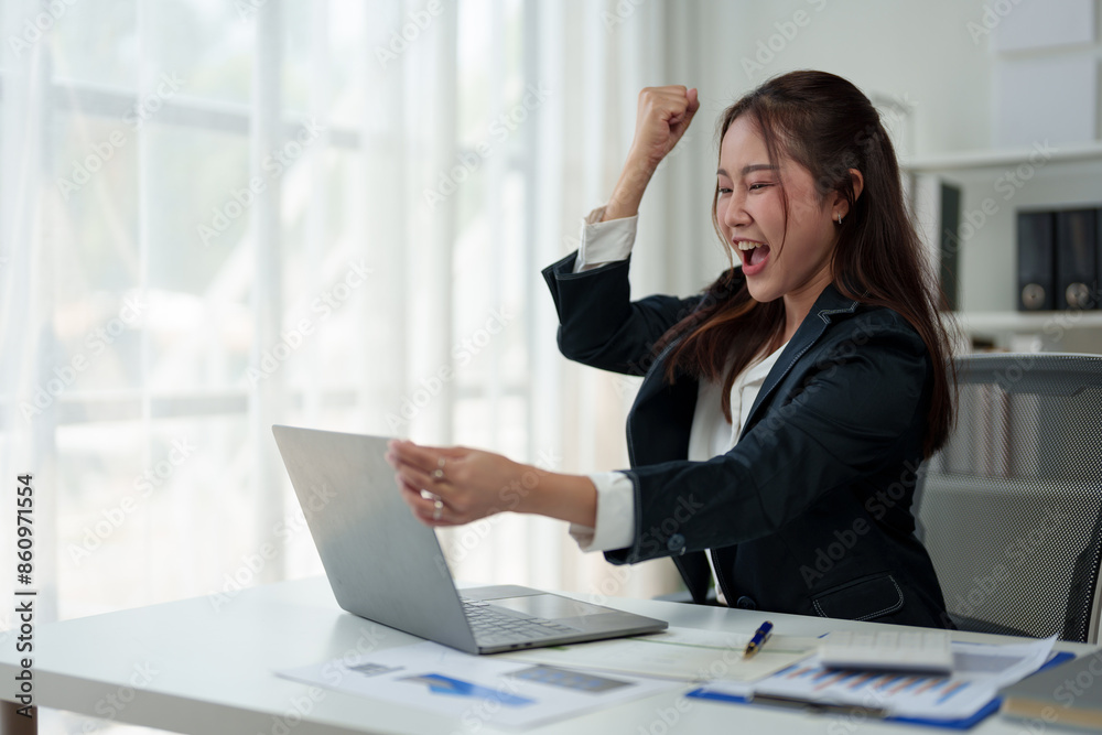 Surprised and happy businesswoman shows joyful expression after viewing news results, business approval results and financial approval results on laptop at office. Startup business growth concept. Surprised and happy businesswoman shows joyful expression after viewing news results, business approval results and financial approval results on laptop at office. Startup business growth concept.