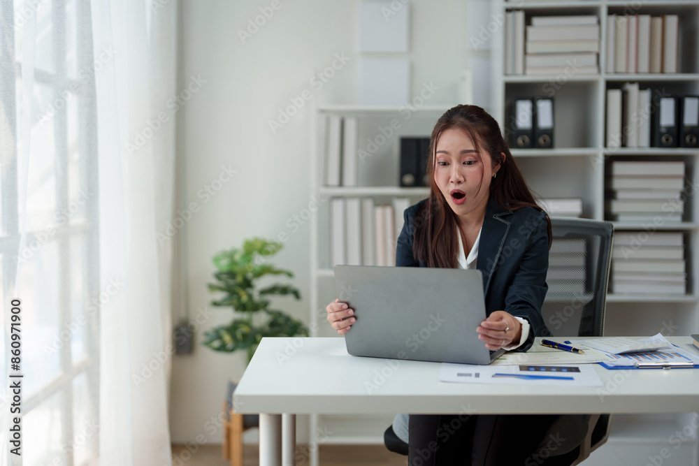 Surprised and happy businesswoman shows joyful expression after viewing news results, business approval results and financial approval results on laptop at office. Startup business growth concept. Surprised and happy businesswoman shows joyful expression after viewing news results, business approval results and financial approval results on laptop at office. Startup business growth concept.