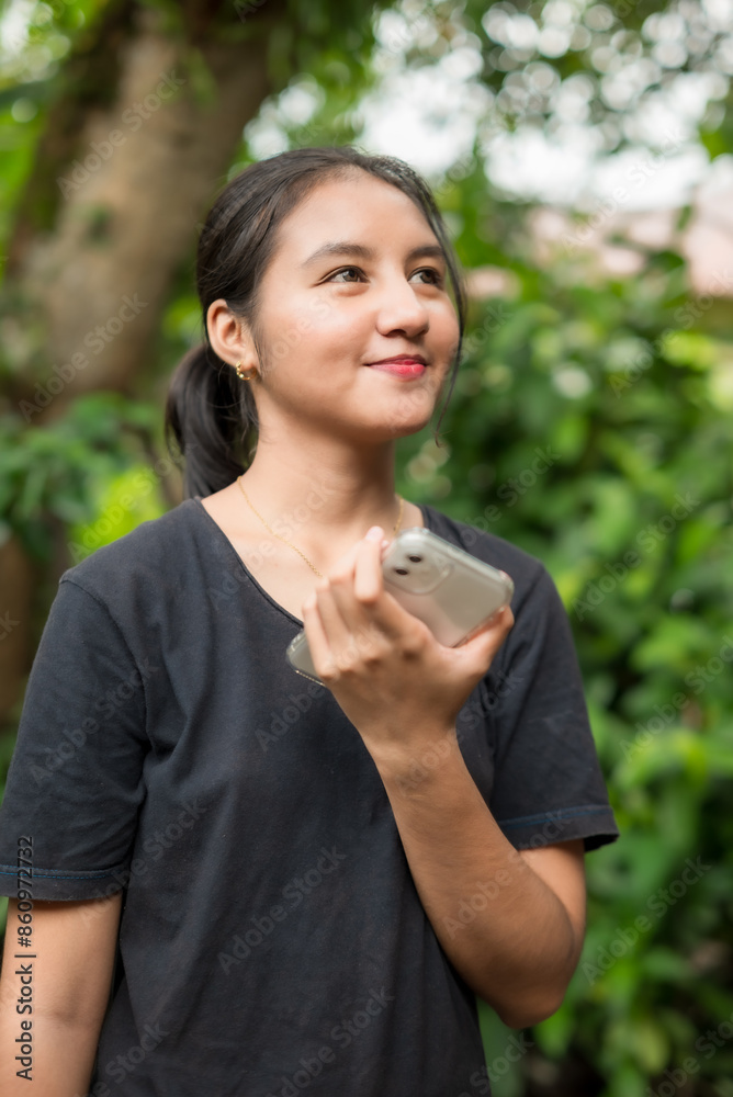 Asian woman playing with smartphone in park Asian woman playing with smartphone in park