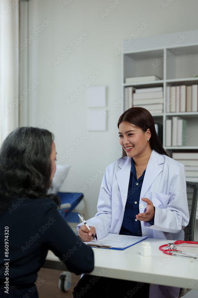 Confident Asian female doctor explains and questions a retired female patient attending a private clinic for treatment and therapy. Health concept, health insurance. Confident Asian female doctor explains and questions a retired female patient attending a private clinic for treatment and therapy. Health concept, health insurance.