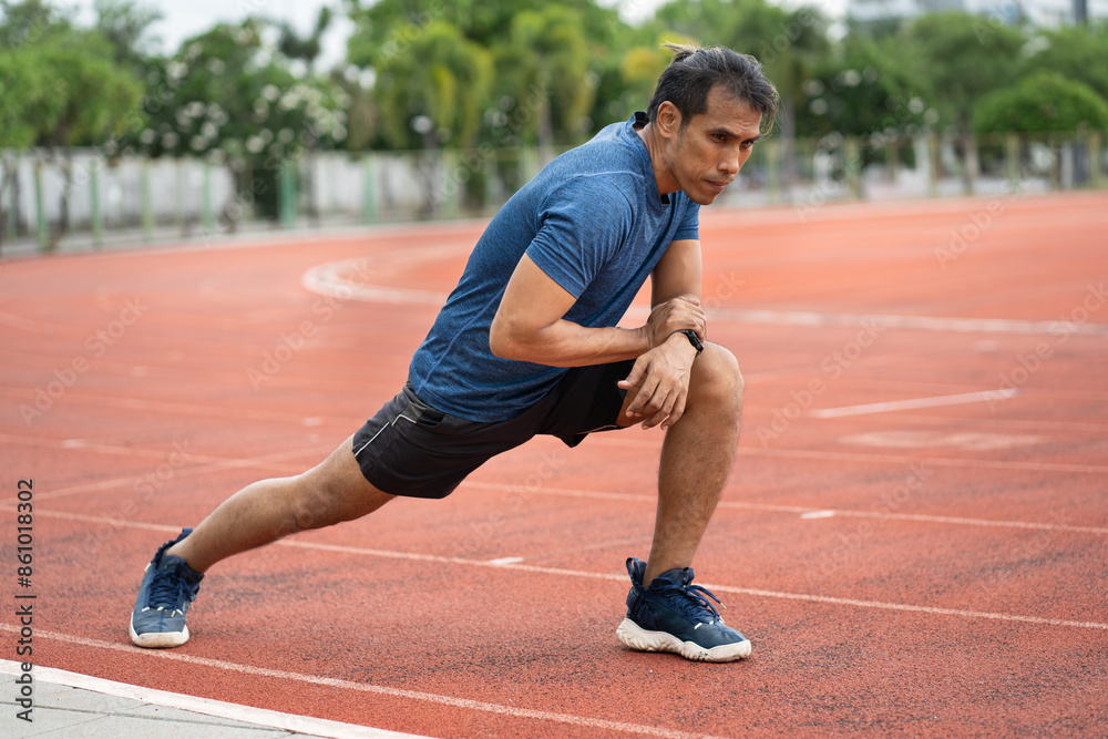 Obraz premium Mature fitness Asia man runner stretching legs before run on racetrack