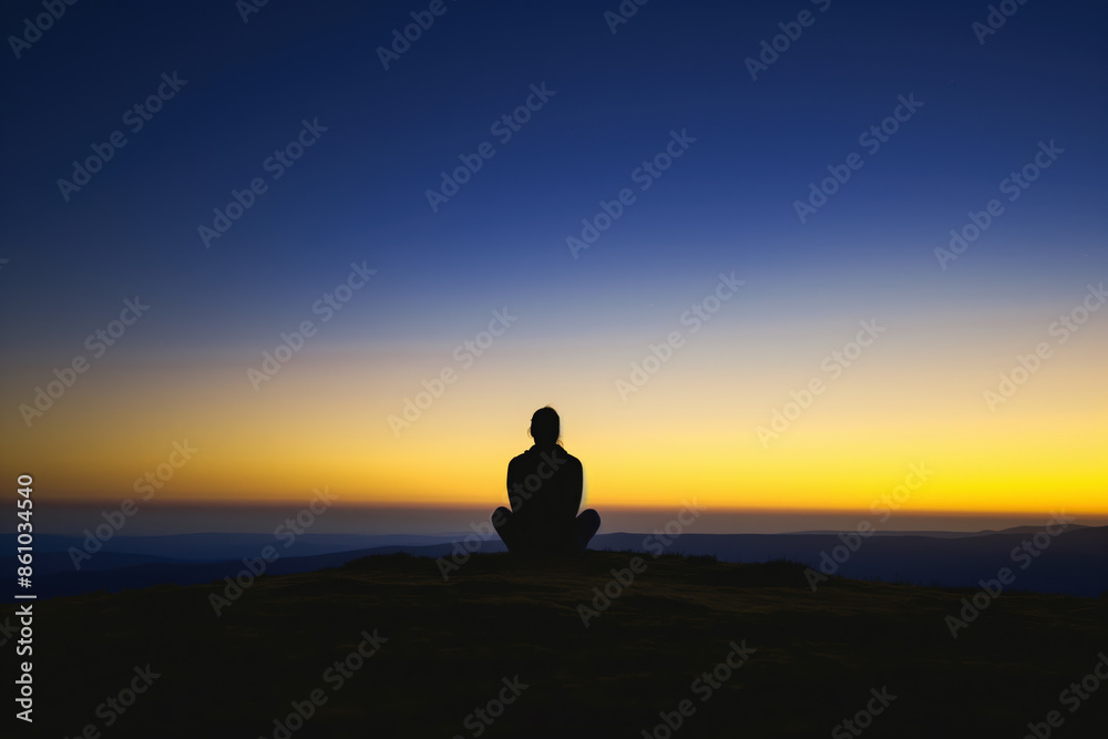 Woman meditating on top of mountain at sunset enjoying peace and freedom Woman meditating on top of mountain at sunset enjoying peace and freedom