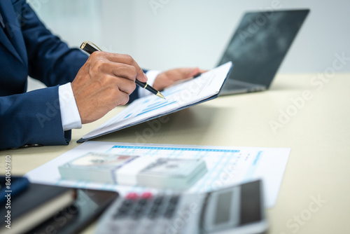 A banker in a suit works at a desk handling loans, analyzing client financial data, providing financial advice, dealing with stocks and the stock market, and studying economic situations. photo