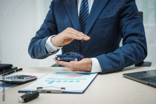 A man in a suit works at his desk selling cars and online car insurance with low interest rates, offering car loans, vehicle financing, and comprehensive vehicle coverage