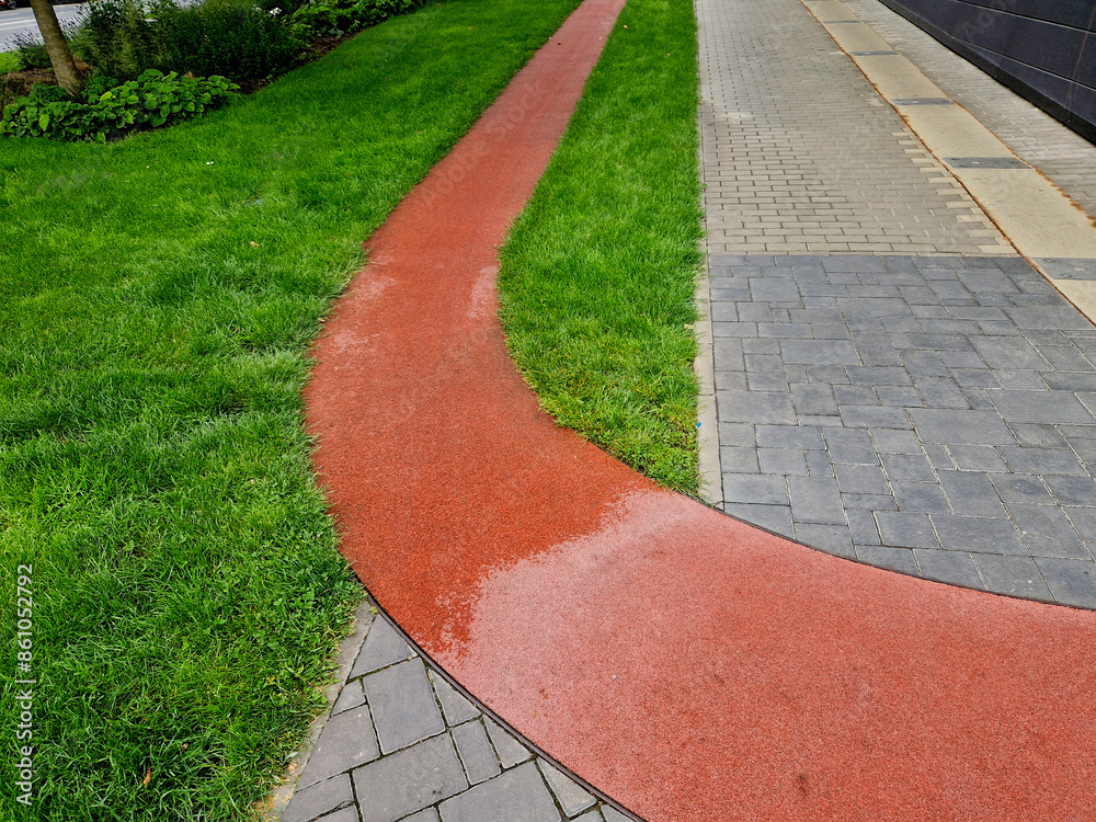 Obraz premium running route made of red rubber material. year-round soft circuit for training in the office district parallel to the sidewalk.
