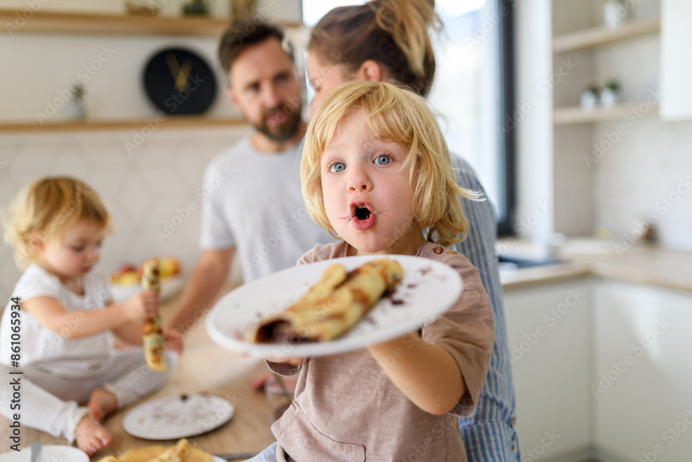 Young nuclear family making pancakes together. Parents and children in kitchen, spending weekend day indoors. Young nuclear family making pancakes together. Parents and children in kitchen, spending weekend day indoors.