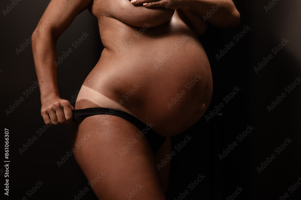 Naklejka premium Pregnant woman pulls back her panties showing instant tan. Vertical photo. 