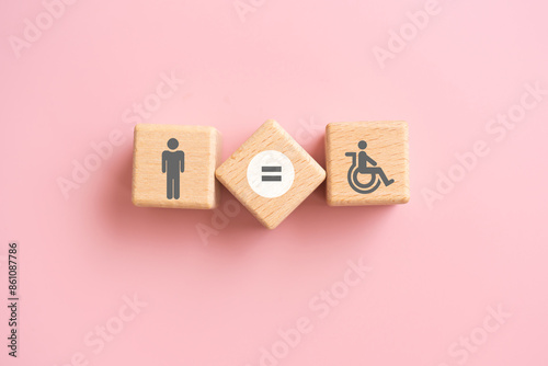 Symbol for equal rights of persons with disabilities. Man , disability person and equal sign on wooden cube blocks with pink background