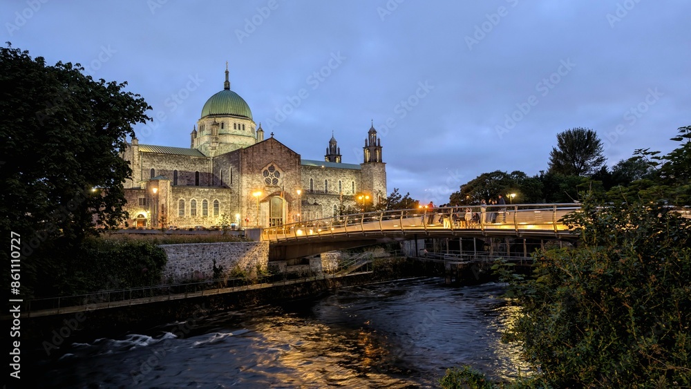 Galway cathedral by night, Salmon Weir Pedestrian bridge over Corrib river, Ireland, historic landmark and architecture