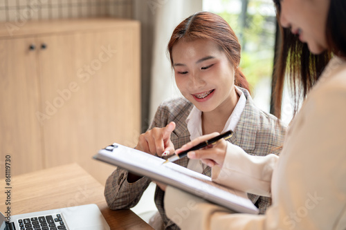 An Asian businesswoman is having a meeting with her colleague, discussing, planning their project.