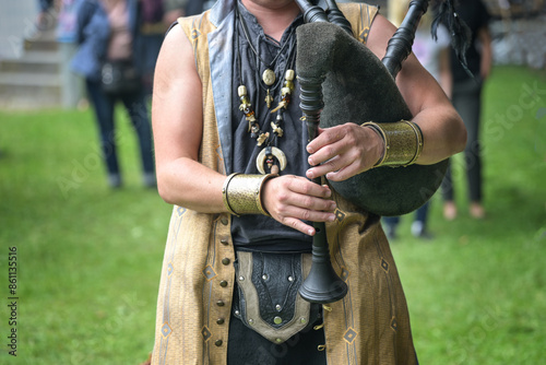 Musician in medieval costume playing the bagpipes made of leather and wood, folk music performance at a middle ages festival event, copy space, selected focus
