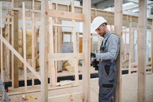Worker carpenter assembling a modular house © Serhii
