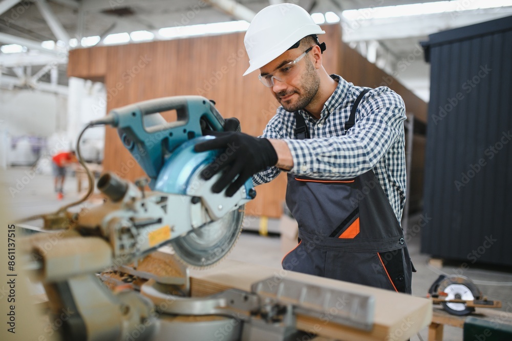 A worker or engineer in a uniform works on a construction site for the manufacture of wooden modular houses A worker or engineer in a uniform works on a construction site for the manufacture of wooden modular houses