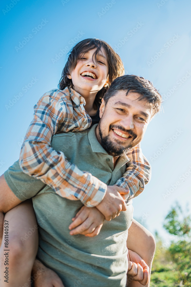 Happy father piggybacking son on sunny day Happy father piggybacking son on sunny day