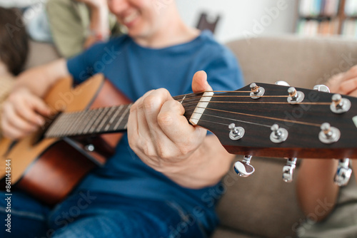 Close-up hand of man on guitar chords at home photo