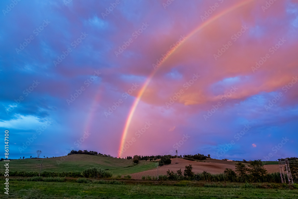 Rainbow at dusk under cloudy sky in Maremma, Tuscany, Italy Rainbow at dusk under cloudy sky in Maremma, Tuscany, Italy