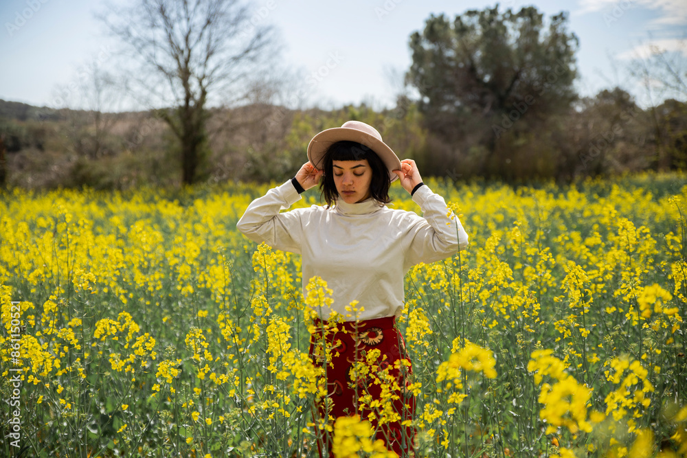 Young woman wearing hat standing in rape field Young woman wearing hat standing in rape field