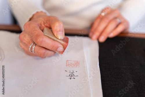 Hand of woman using Japanese stamp on paper photo