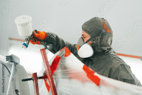 Canvas Print Auto painter painting a car with vaporizer gun inside a paint booth