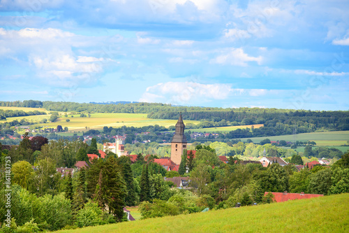 A picturesque view of Hofgeismar, a small town in Germany. The city is situated among green hills, and in the center, the dome of the church stands out. A beautiful landscape against the sky. photo