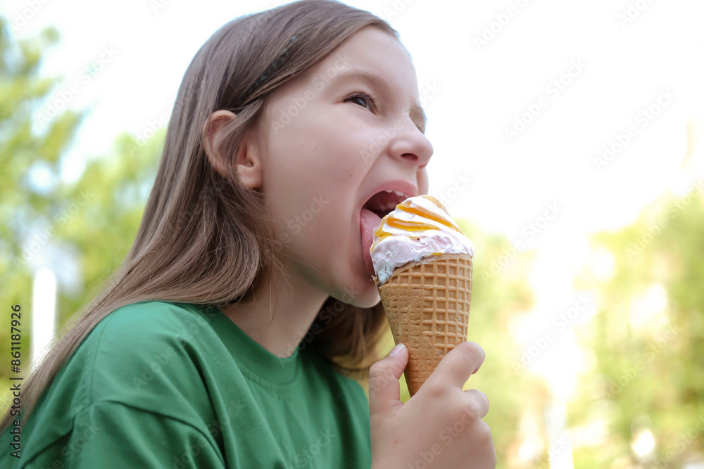 Happy and contented girl eats ice cream outdoors in summer when it's hot outside. Concept of baby food and happy childhood. Summer holidays and fun. Selective focus.