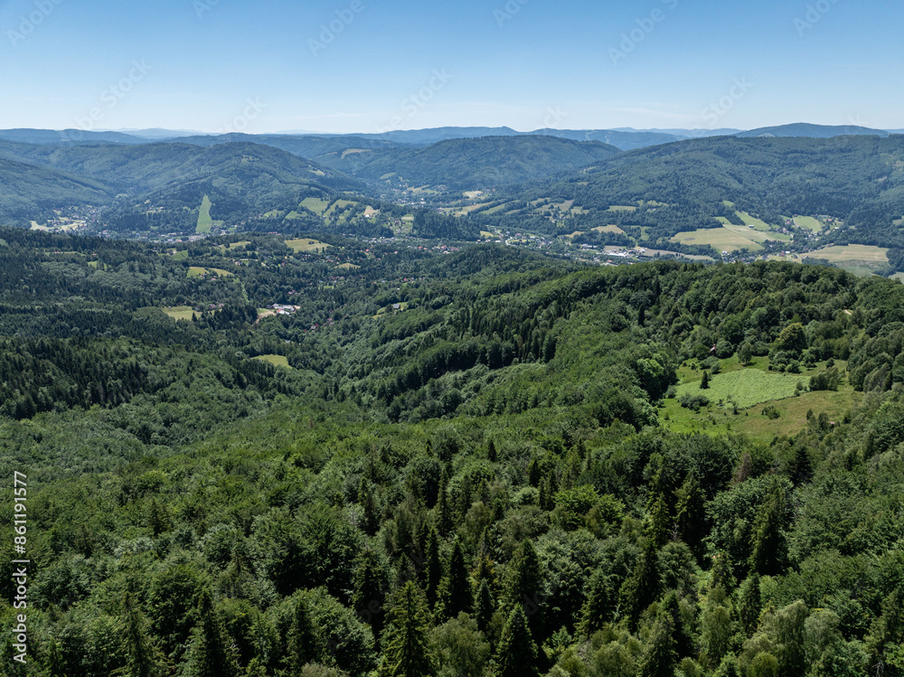 Obraz premium Drone fly above green mountains in summer. Polish green mountains and hills aerial drone photo. Drone view in Beskid mountains, Blatnia. Summer green forest on Blatnia. Beskid mountains in Jaworze.
