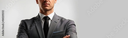 Man in suit with crossed arms. Plain background. Business confidence and authority.