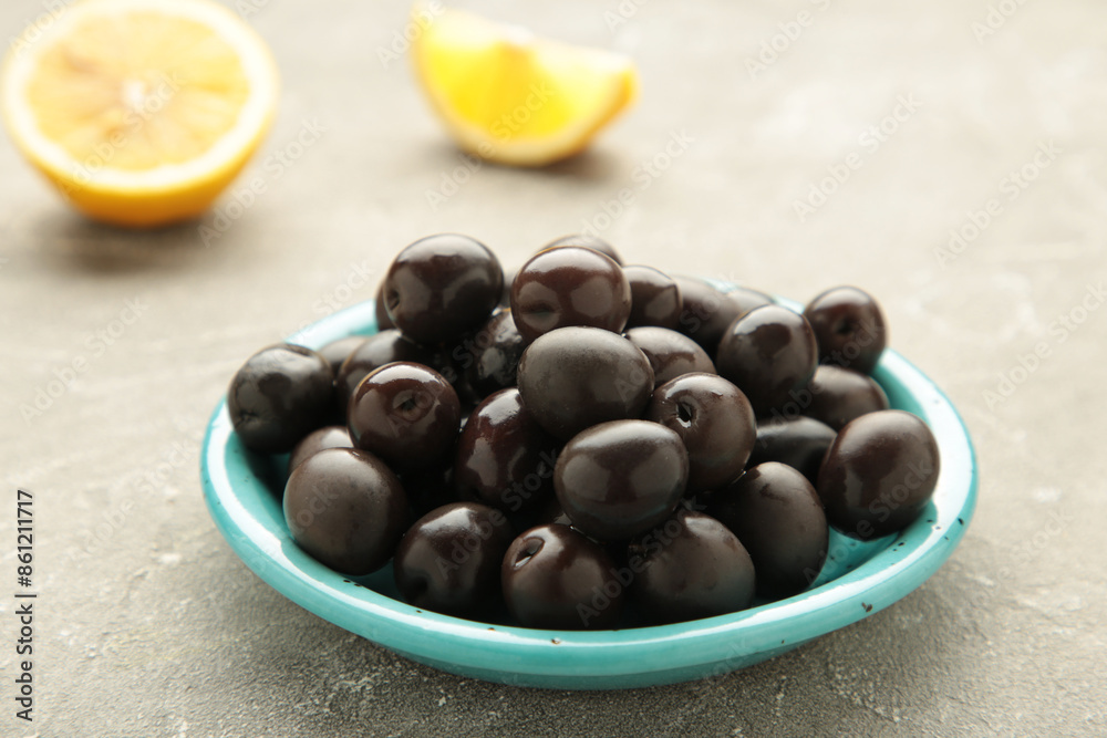Black olives with lemon on grey concrete background