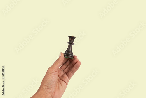 Black male hand holding a black queen chess figure isolated on green background