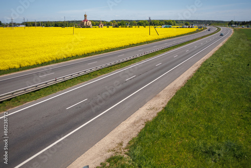 Photos asphalt highway with a median along a rapeseed field