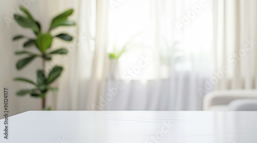 The blurred empty table top in the living room had a light grey curtain and window behind it. A modern interior design was shown with a blurred green plant on the side of the wall and a wooden shelf 