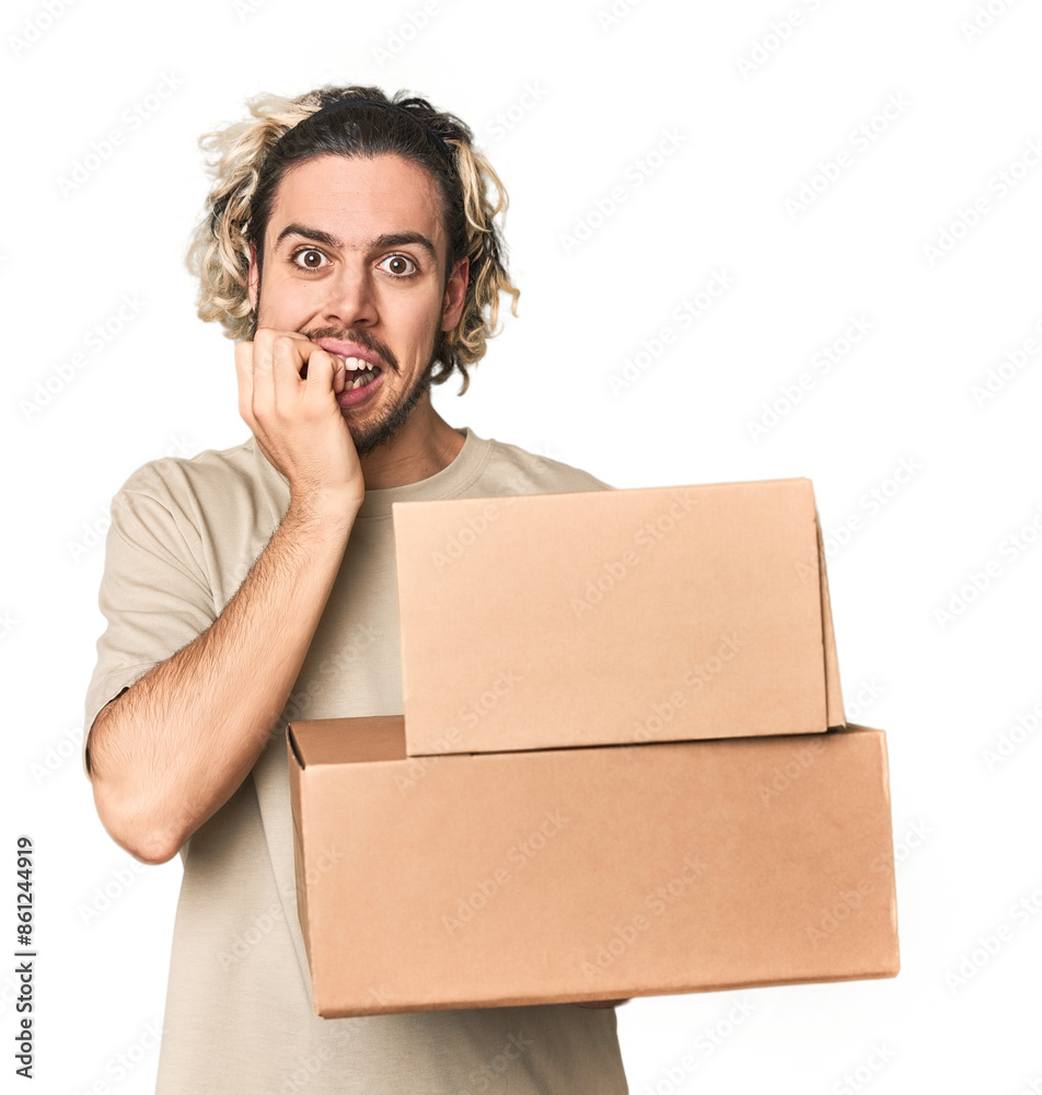 Young man with cardboard boxes in studio biting fingernails, nervous and very anxious. Young man with cardboard boxes in studio biting fingernails, nervous and very anxious.