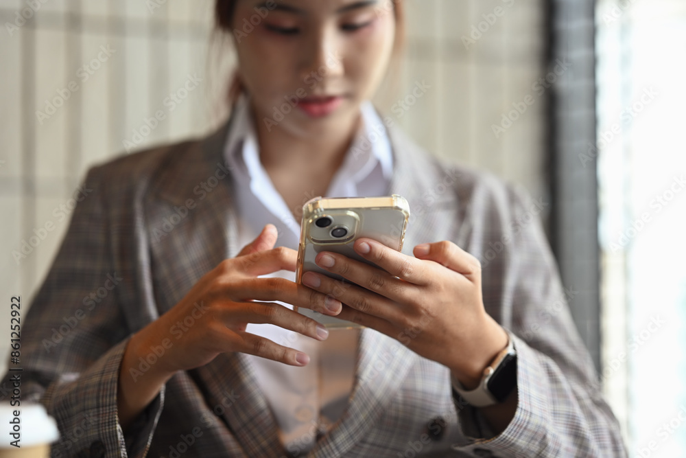 Cropped shot of asian female entrepreneur sitting at desk checking mobile phone apps Cropped shot of asian female entrepreneur sitting at desk checking mobile phone apps