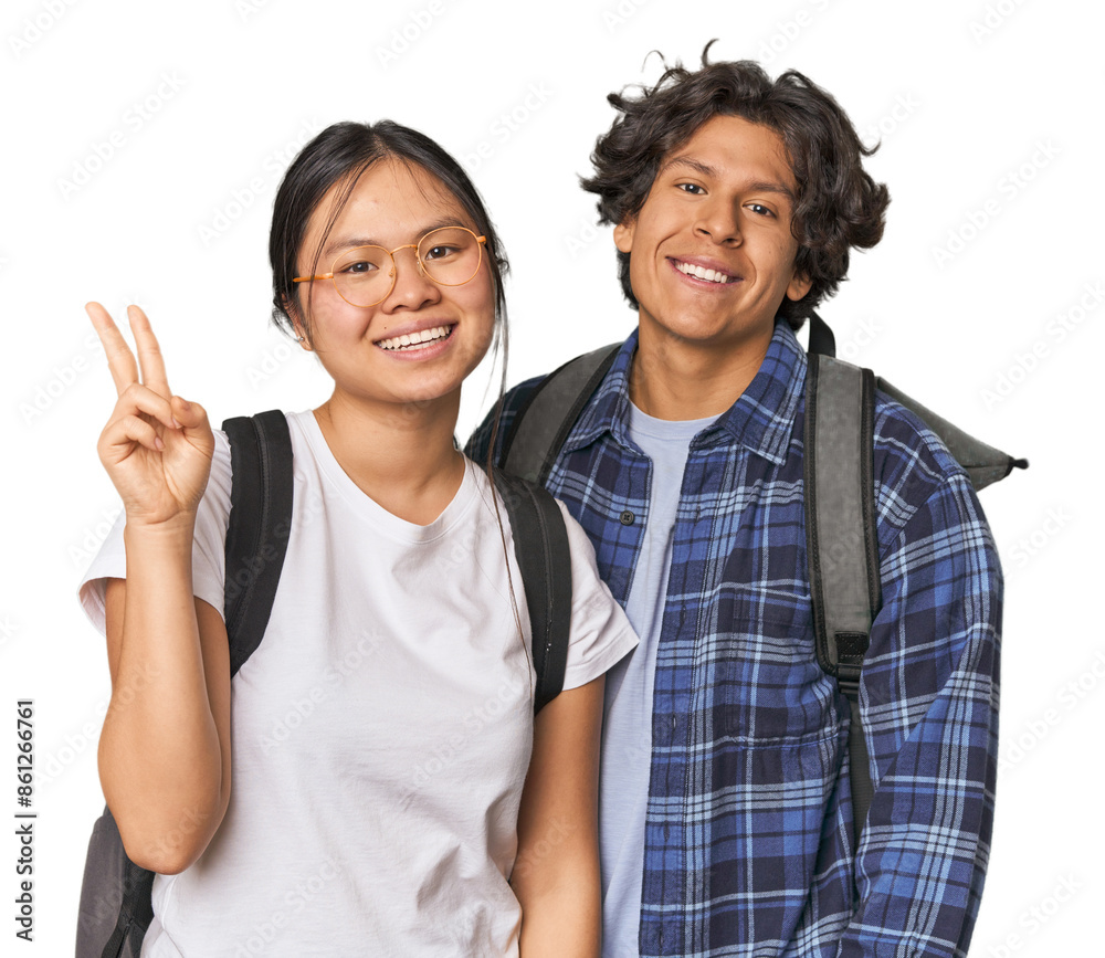 Young interracial student couple studying joyful and carefree showing a peace symbol with fingers. Young interracial student couple studying joyful and carefree showing a peace symbol with fingers.