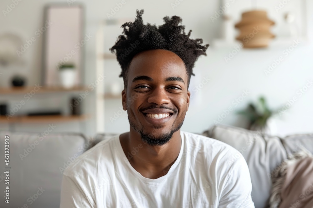 Portrait of a glad afro-american man in his 20s smiling at the camera while standing against crisp minimalistic living room Portrait of a glad afro-american man in his 20s smiling at the camera while standing against crisp minimalistic living room