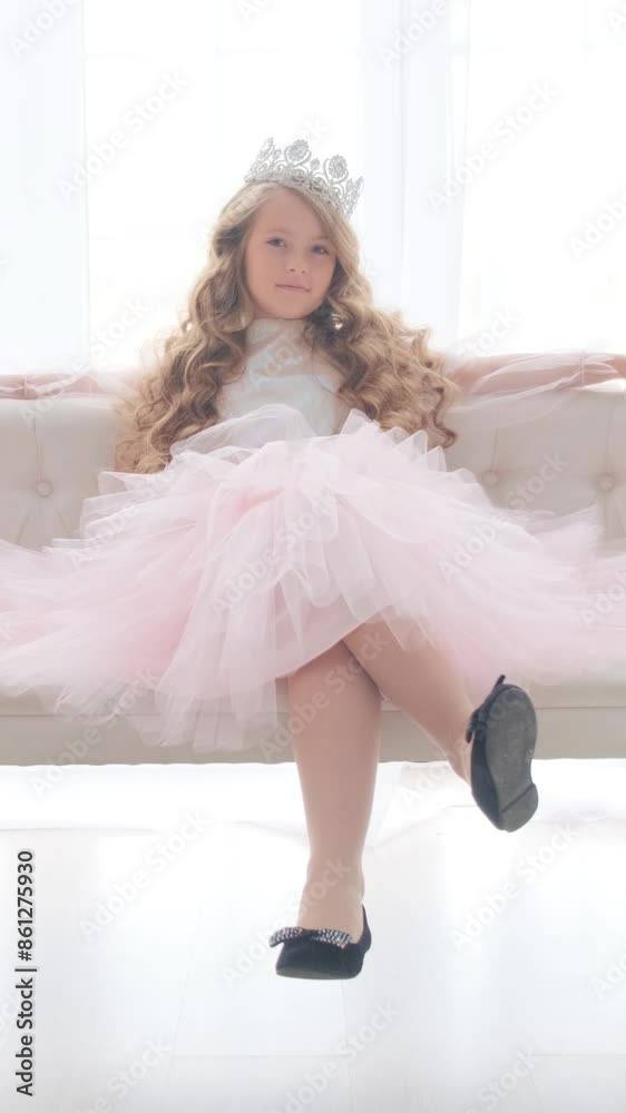 Portrait of a cute little princess with a crown on her head. The girl winks and smiles at the camera. Vertical video. Portrait of a cute little princess with a crown on her head. The girl winks and smiles at the camera. Vertical video.