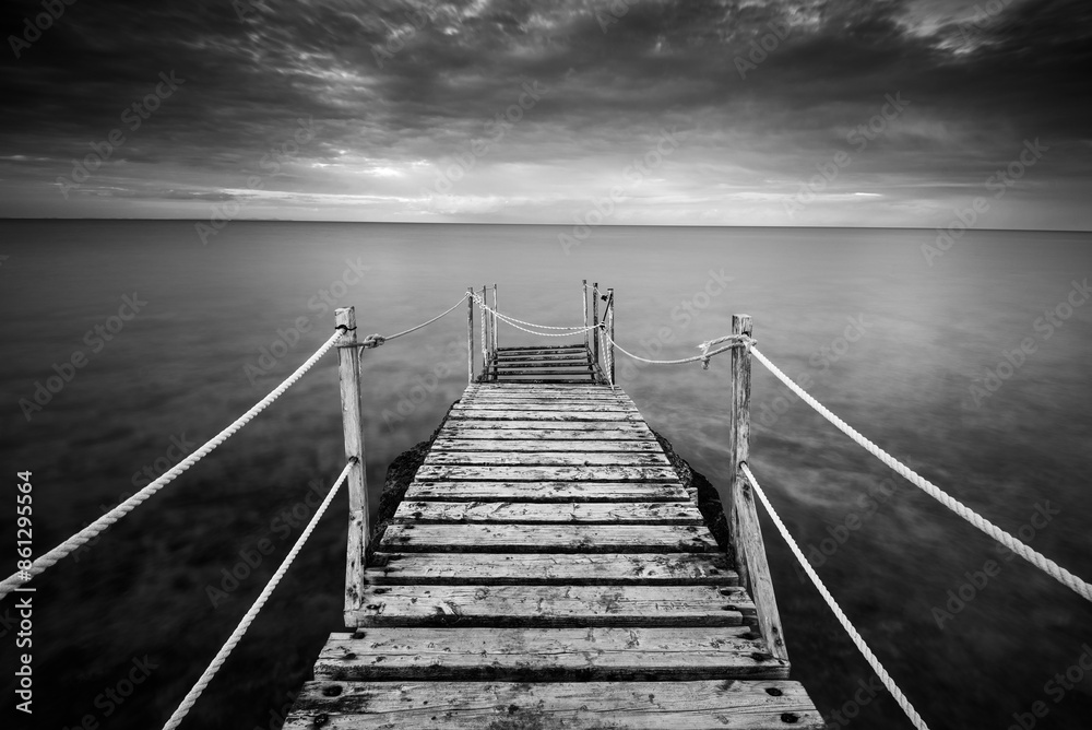 Obraz premium Long wooden pier in the sea at sunset.