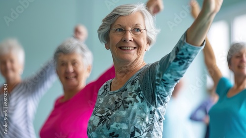 A group of elderly women smiling and participating in a fitness class, raising their arms in a bright, airy room.