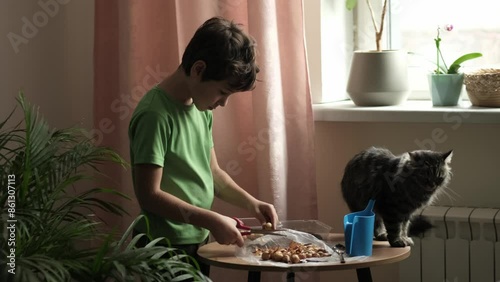 A boy in a green shirt waters soil in plastic containers while preparing to plant onions. The scene illustrates teaching children sustainable practices and the concept of an indoor vegetable garden. photo