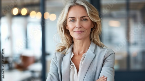 A confident, corporate woman standing with her arms crossed in a modern office setting, reflecting professionalism, leadership, and a calm and determined attitude.