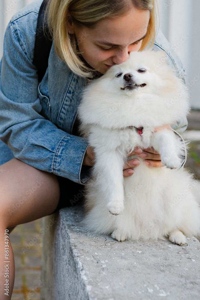 beautiful young happy girl with short hair walks with her Pomeranian dog on the street in summer. Sunny weather in the city in the park beautiful young happy girl with short hair walks with her Pomeranian dog on the street in summer. Sunny weather in the city in the park