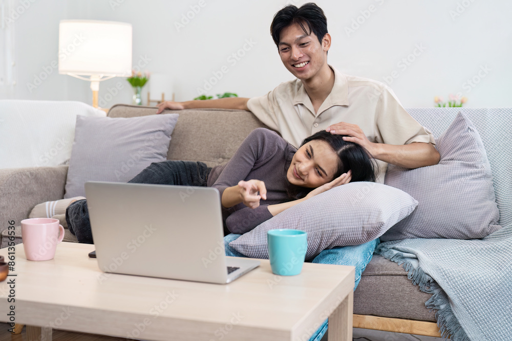 Happy Couple Relaxing at Home on Couch Watching Laptop Together with Coffee Mugs in Cozy Living Room Happy Couple Relaxing at Home on Couch Watching Laptop Together with Coffee Mugs in Cozy Living Room