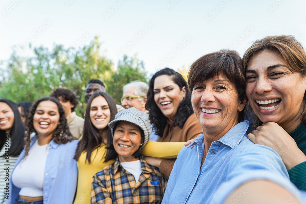 Group of multigenerational people taking selfie with phone camera - Multiracial friends of different ages having fun together - Main focus on two right women faces Group of multigenerational people taking selfie with phone camera - Multiracial friends of different ages having fun together - Main focus on two right women faces