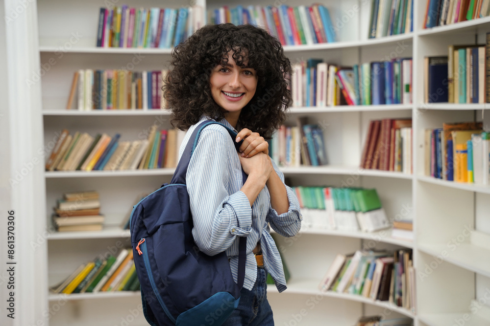 Cute woman in the library smiling nicely and looking contented Cute woman in the library smiling nicely and looking contented