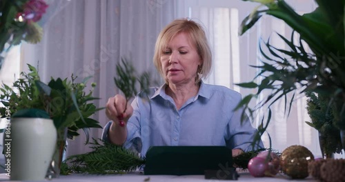 Professional woman florist takes care of seedlings in floral studio and looking at camera