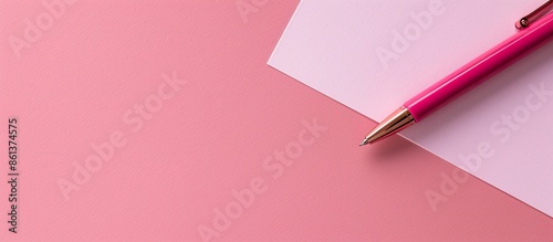 Blank note paper and a pen on a soft pink background from a top view, ideal for a back-to-school concept with copy space image.