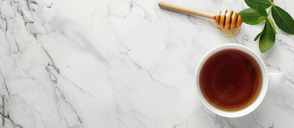 Fresh black tea and honey dipper arranged elegantly on a white marble surface from a top-down perspective with copy space image; a tea concept captured in a square crop photo. Fresh black tea and honey dipper arranged elegantly on a white marble surface from a top-down perspective with copy space image; a tea concept captured in a square crop photo.